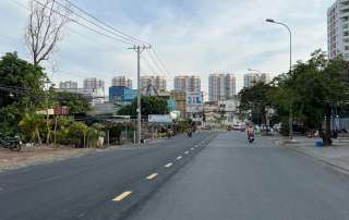 Hình ảnh thực tế con đường Nguyễn Hoàng vừa mới được nâng cấp thảm nhựa rộng rãi, hai bên đường là các dãy nhà phố sầm uất và xe cộ đang lưu thông nhộn nhịp.